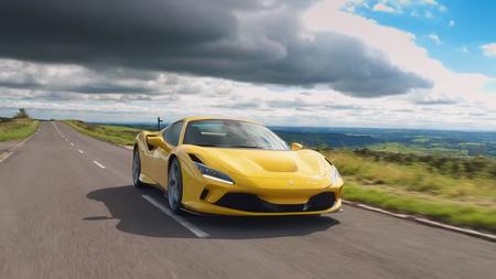 Ferrari F8 Spider Yellow Ferrari F8 Spider drives down road with heavy cloud behind