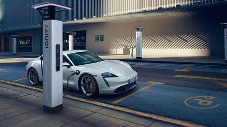 Porsche Taycan charging in public White Porsche Taycan charging in a blue public charging spot