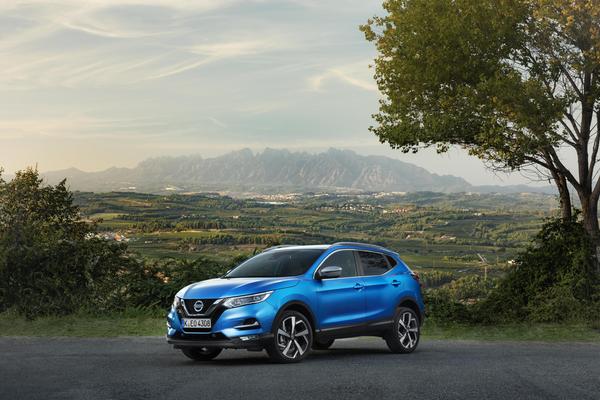 Blue Nissan Qashqai parked by tree in mountainous area