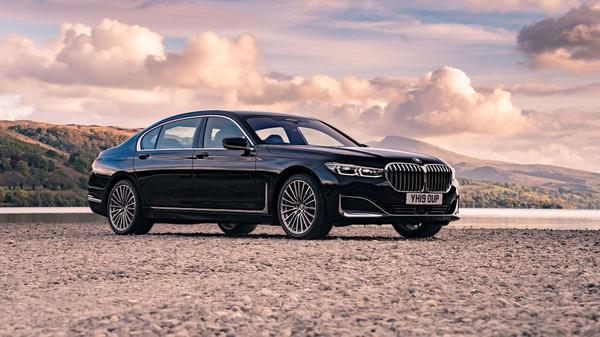Black BMW 7 Series saloon parked on a rocky coastline