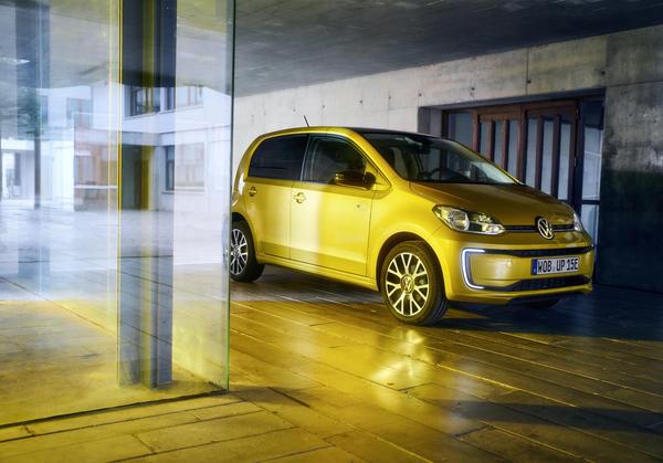 Yellow VW E Up electric car parked in a gold-lit garage