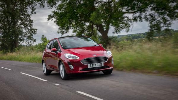 Red Ford Fiesta driving on a country road