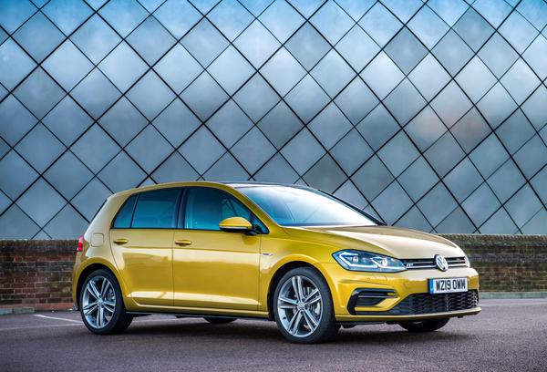 Yellow Volkswagen Golf parked in front of modern glass structure