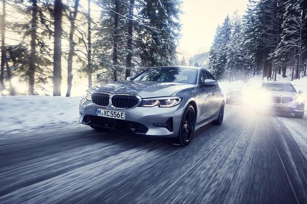 Silver BMW 330e driving through a snowy forest