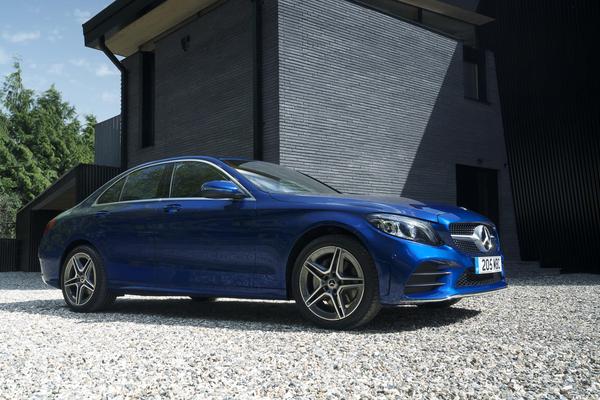 Blue Mercedes C Class lease car parked outside a grey house