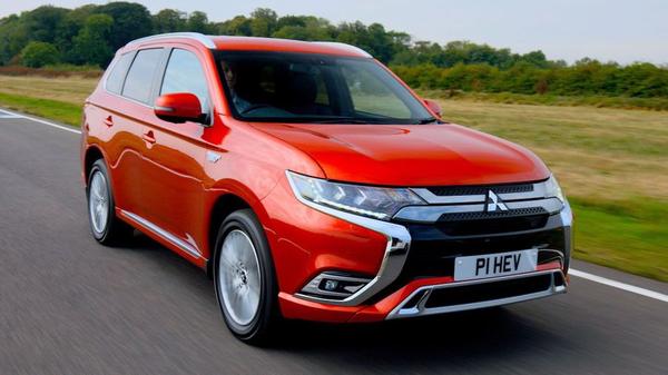 Red Mitsubishi Outlander Hybrid driving on a country lane