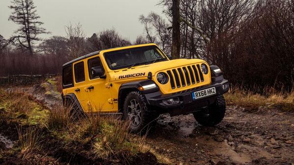 Yellow Jeep Wrangler offroading through mud