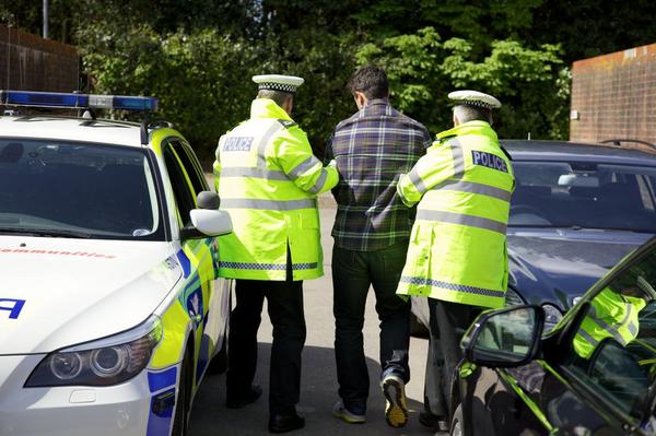 Police officers arresting a stolen car dealer