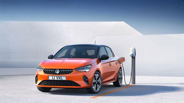 Orange Vauxhall Corsa E electric car charging in a white space
