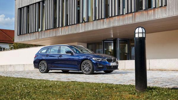 Blue BMW 3 Series Touring parked in front of a modern home