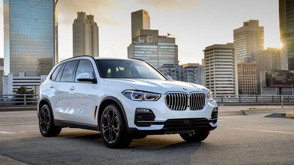 White BMW X5 parked against a cityscape, early in the morning