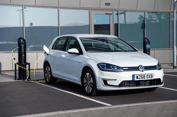 White Volkswagen e-Golf lease electric car charging outside an office