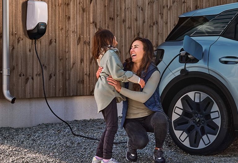 Women and child hugging and charging their Ford Explorer at home