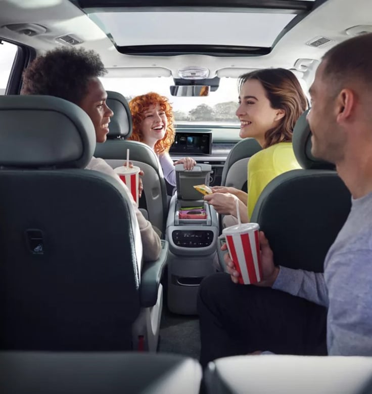 four people in the car smiling with plenty of space
