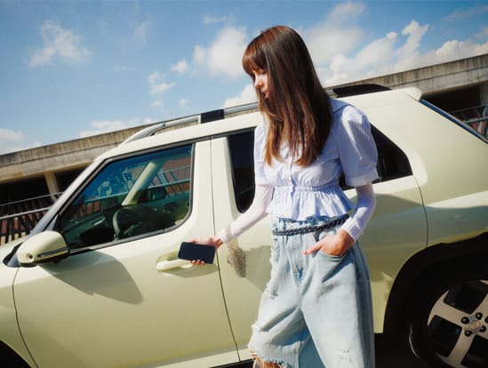 A woman touching a phone to her Inster car door