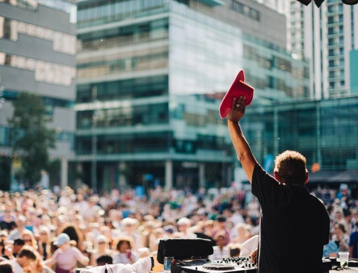 The We Invented the Weekend festival for the 15th to 16th June 2024 A DJ at their mixing desk and waving their hat at the We Invented the Weekend festival