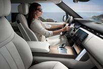 An interior view of a stylish woman wearing sunglasses, driving a Range Rover