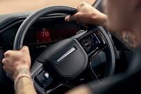 A person with their hands on the steering wheel, driving a Range Rover Sport