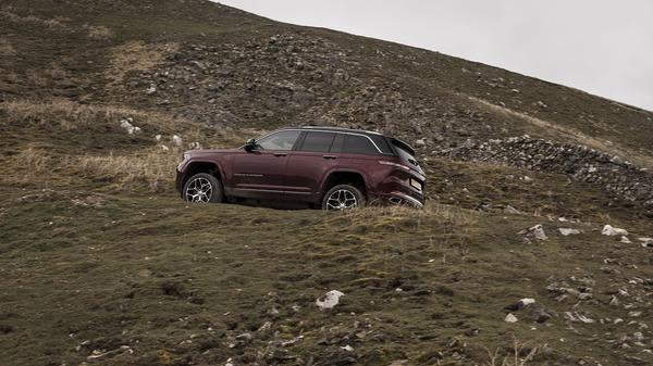 2024 Red Jeep Grand Cherokee side view climbing rocky hill